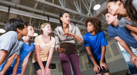 Teacher giving instructions to students in a gym for physical education 